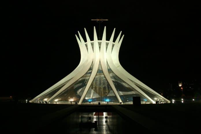 Fotografia da Catedral de Brasília durante a noite, iluminada por feixes de luz em sua base.