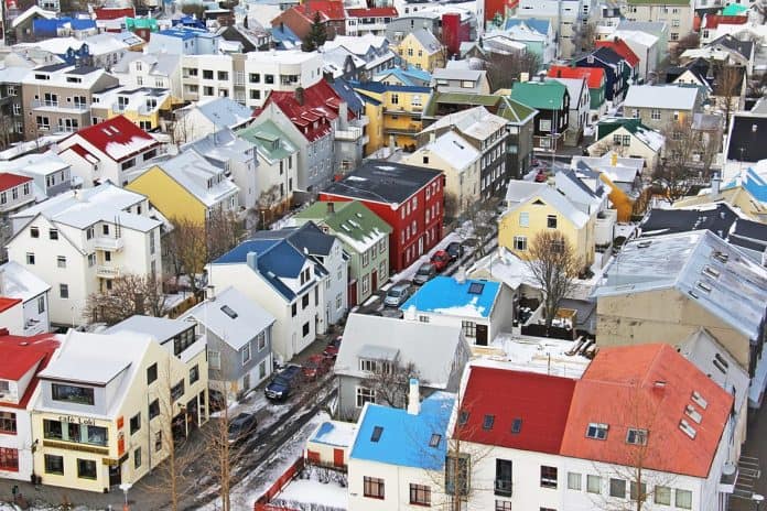 Fotografia aérea de um bairro localizado na capital da Islândia, Reykjavik, composto por casas coloridas com os telhados cobertos de neve.