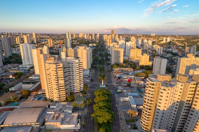 Fotografia vista da cidade de Campo Grande, Mato Grosso do Sul, com visão dos edifícios, avenidas e residências. O céu está azul