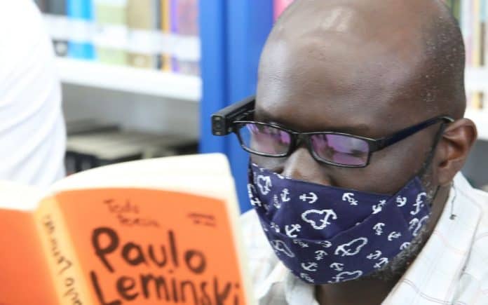 Fotografia de homem lendo livro de Paulo Leminski usando leitor digital com inteligência artificial, no projeto Fábricas de Cultura, do Governo do Estado de São Paulo