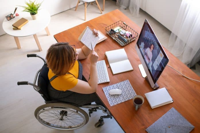 Fotografia de mulher com deficiência em cadeira de rodas em aula online