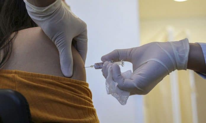Pessoa aplicando vacina onde aparecem as mãos do profissional de saúde aplicando o imunizante contra a covid-19