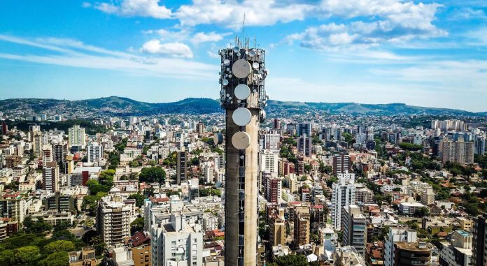 Fotografia de antena de telefonia com amplo cenário da cidade de Porto Alegre