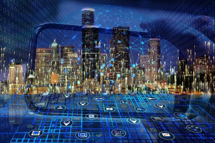 Reprodução de imagem/ilustração de cidade inteligente, com várias conexões de tecnologias interligadas à tela de um celular em referência a cidade