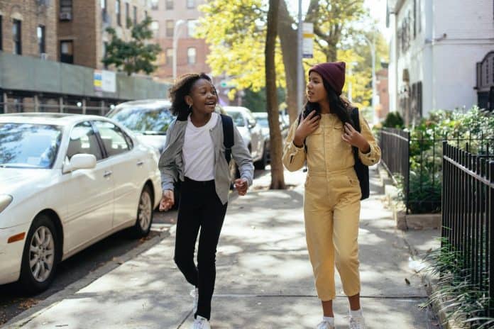Fotografia com fundo claro de duas crianças caminhando em espaço urbano relacionado à cidades inteligentes