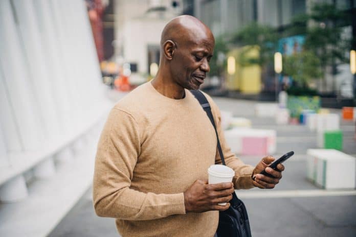 Fotografia de home com celular em cidade em alusãoà amizade entre membros da cidade